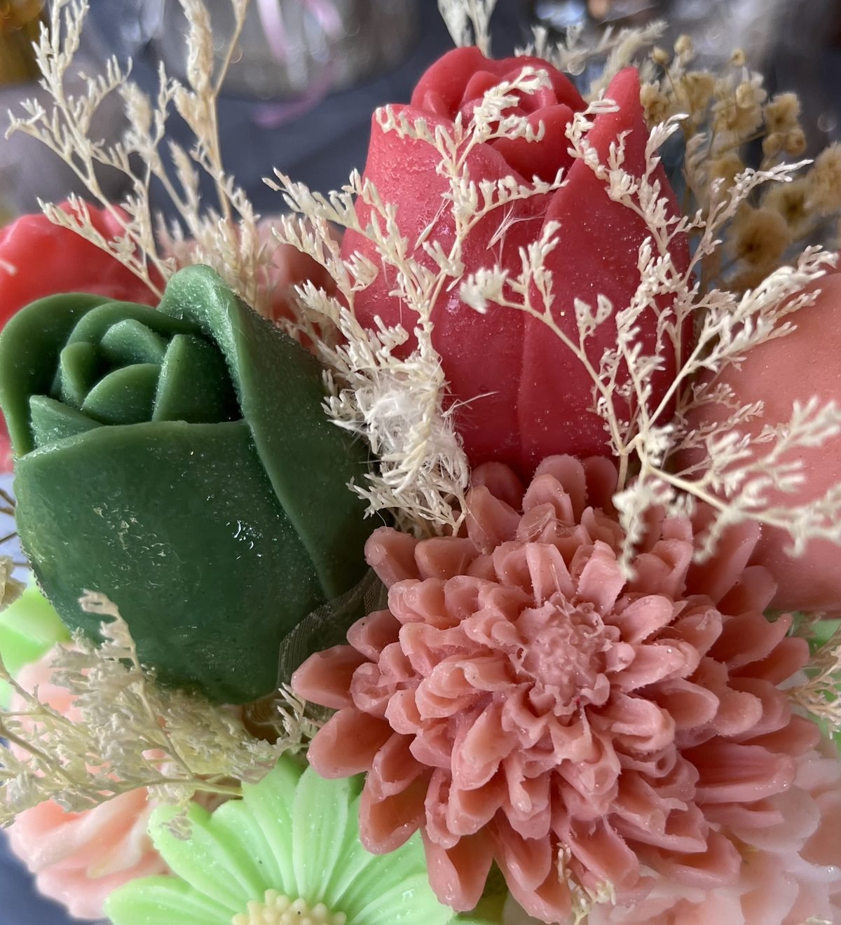 Close-up of a green soap rose, a coral soap chrysanthemum and dried filler