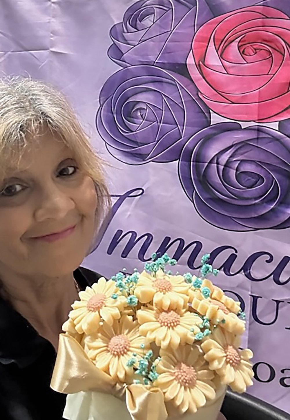 Sharon Spaull holding a bouquet of cream soap daisies at a market stall
